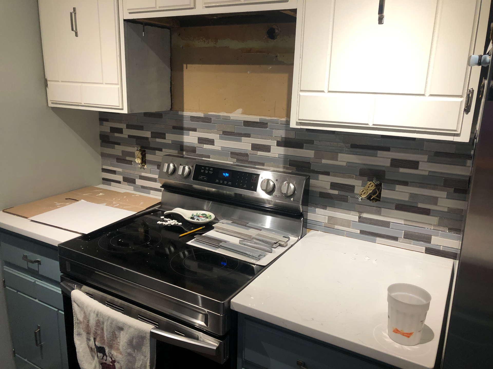 Finished kitchen backsplash installation with linear multi-tone tile behind the range