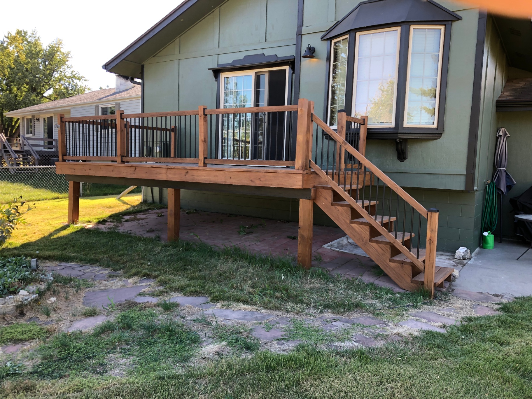 Finished cedar-toned deck after the rebuild — fresh stain, railings, and metal balusters