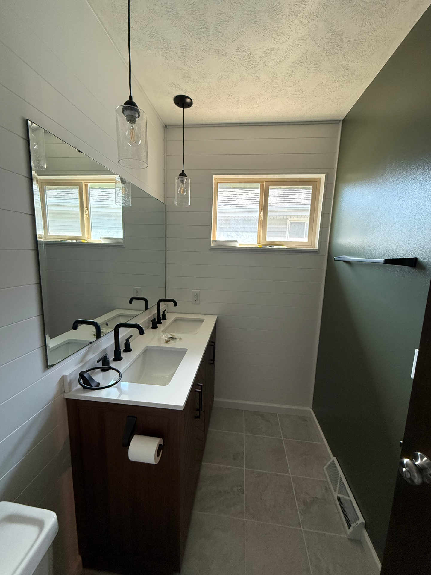 Finished bathroom remodel with double vanity, shiplap walls, and new tile flooring