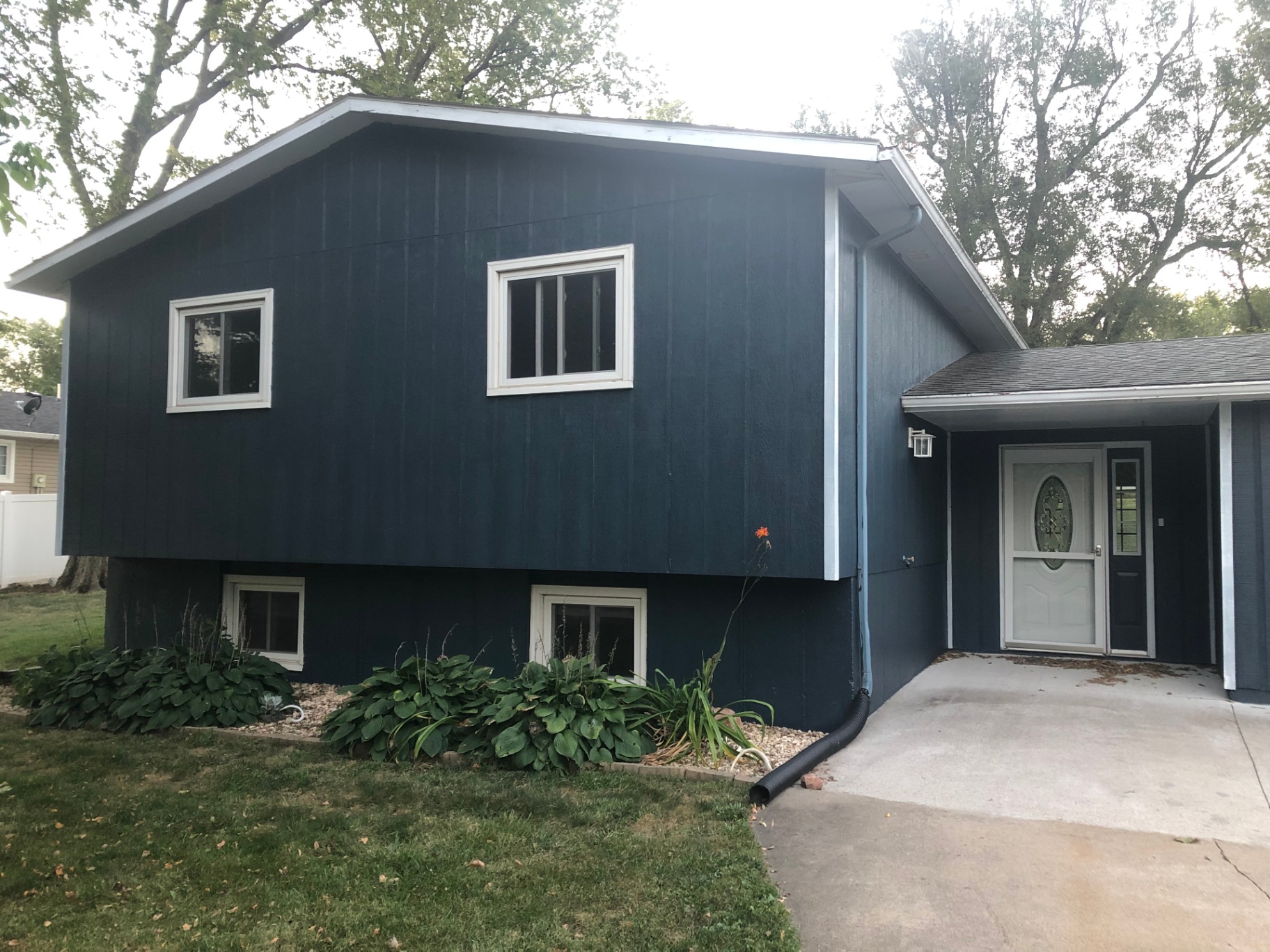 Same split-level home after — repainted a deep navy blue with crisp white window trim for a clean, modern look